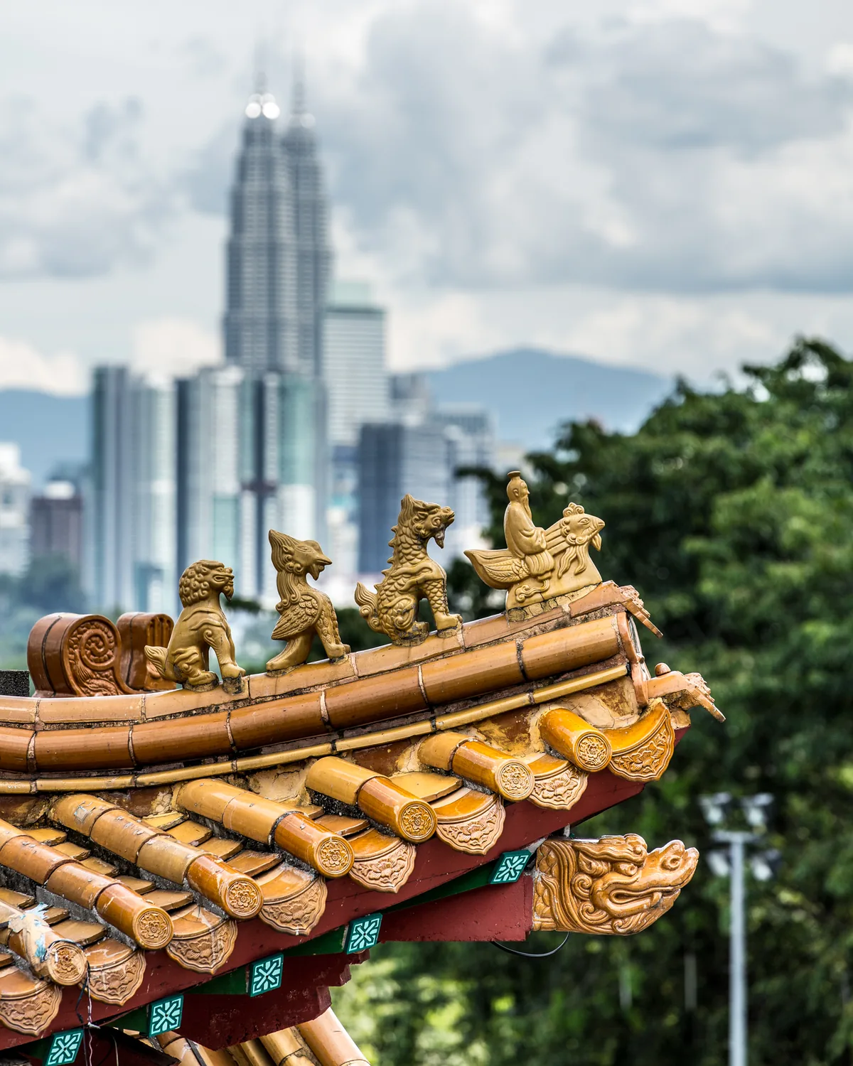 Petronas Towers rising behind a traditional temple roof in Kuala Lumpur